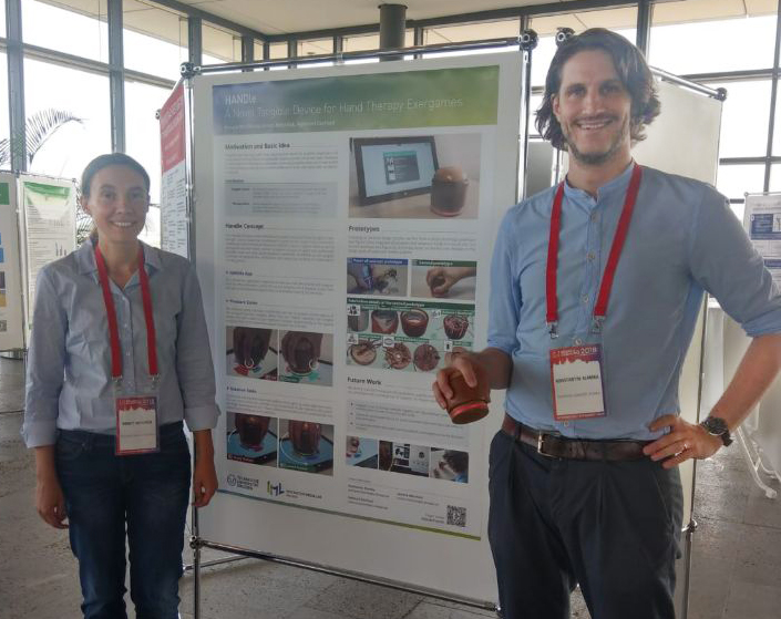 Konstantin Klamka and Annett Mitschick in front of her poster. Konstantin holds the tangible device in his hand.